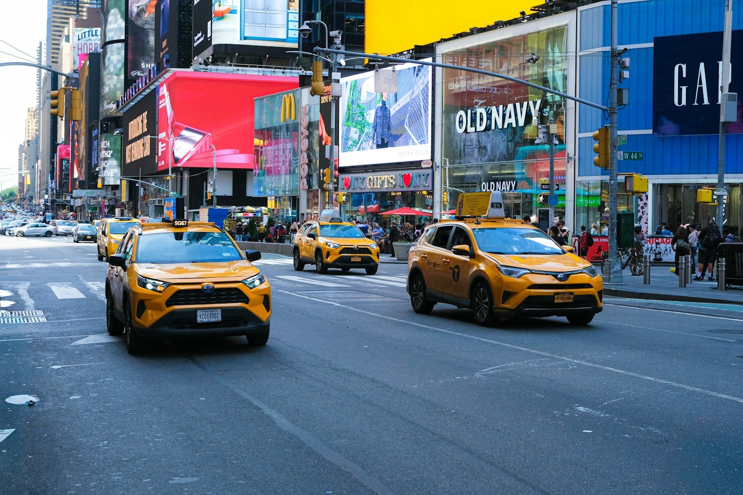 Yellow taxis moving through a busy city street